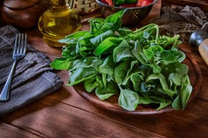 Fresh leaves of spinach on rustic wooden table.